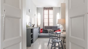 A hallway leading to a dining area with a table and chairs, a sofa, and a window with curtains. - Cozy Elegant 2BR Apartment (Valletta)