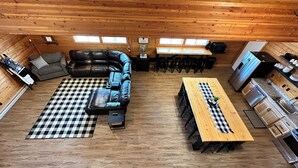 Un intérieur de chalet chaleureux avec un tapis à carreaux, un canapé en cuir, une table à manger et un coin cuisine.