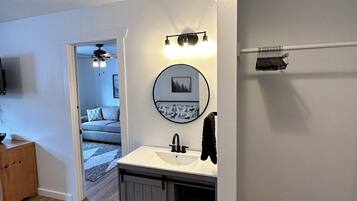 A modern bathroom with a white sink, a mirror, and a ceiling fan.
