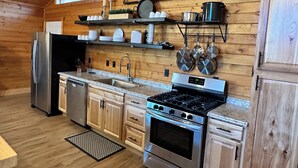 Une cuisine moderne avec des murs en bois, un réfrigérateur en acier inoxydable, un évier et une cuisinière.