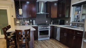 Una cocina moderna con armarios de madera oscura, electrodomésticos de acero inoxidable y una isla central con asientos.
