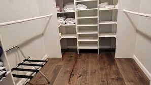 Un vestidor con suelo de madera y estanterías blancas.