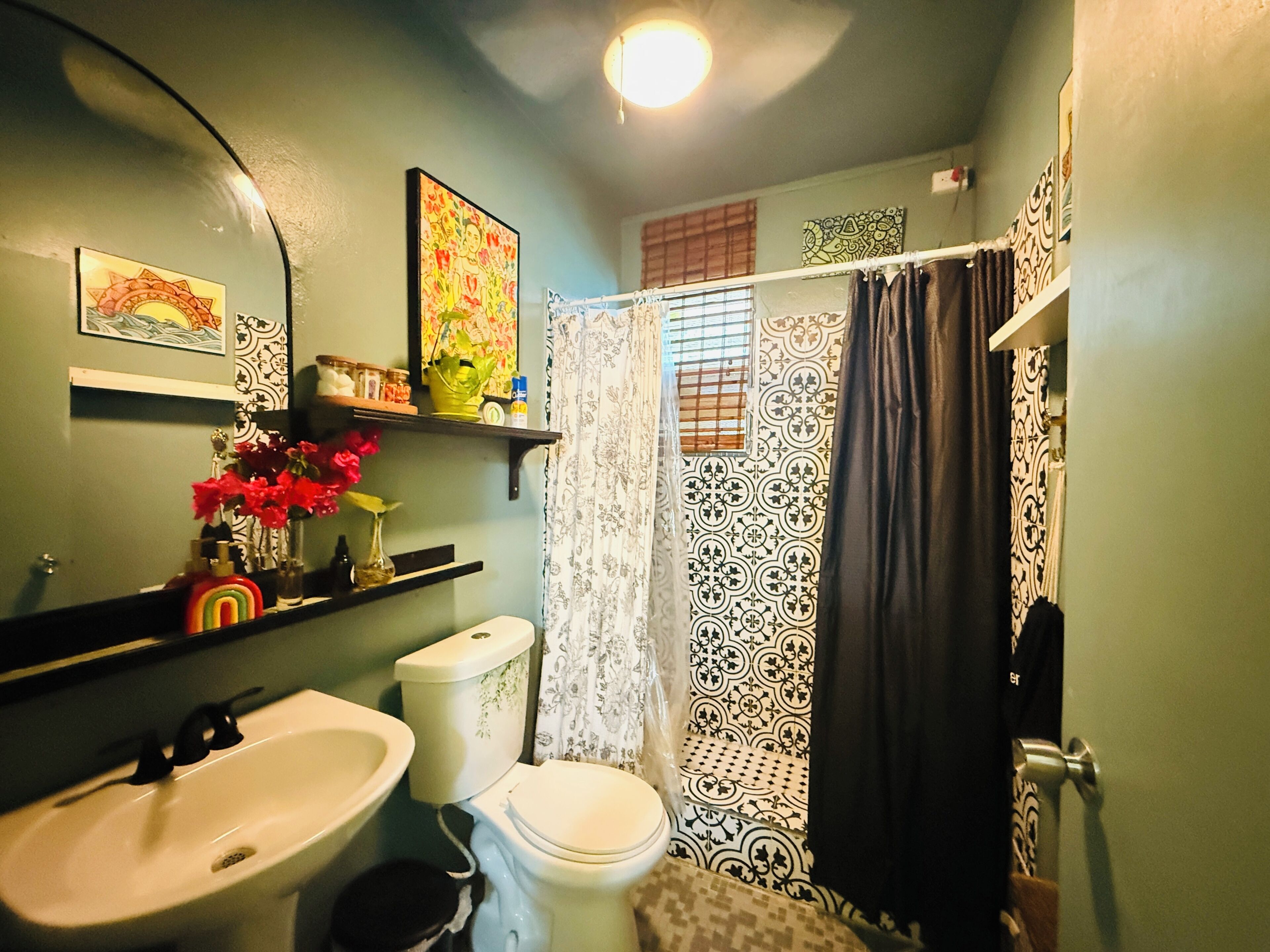 A bathroom with a sink, toilet, and shower curtain.