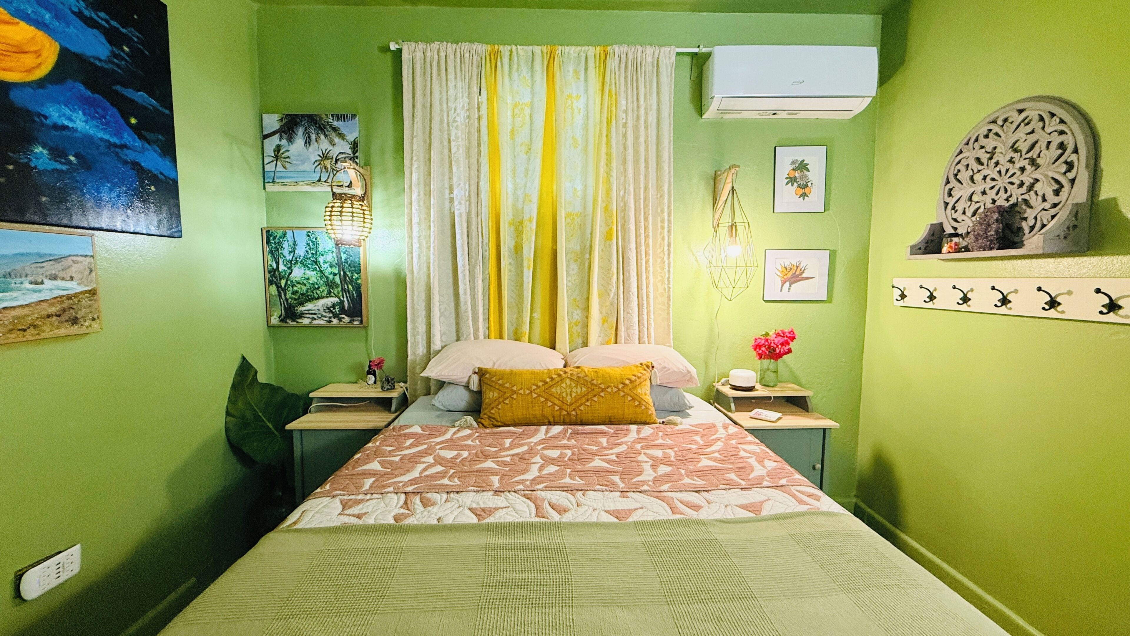 Un dormitorio con cama, cortinas, decoración en la pared, aire acondicionado y un estante con objetos decorativos.