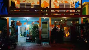 A two-story building with a balcony, outdoor seating area, and string lights. - LoveSoulBeautiful (Luquillo)