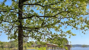 A lakeside cabin with a dock extending into the water, surrounded by trees and grassy areas.
