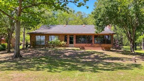 A brick building with a large window, a covered porch, and a lawn.