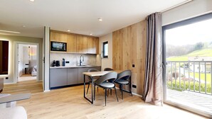 A modern kitchen with wooden cabinets, a built-in microwave, and a dining area with a table and chairs. - Stay Here Living  (Thiersee)