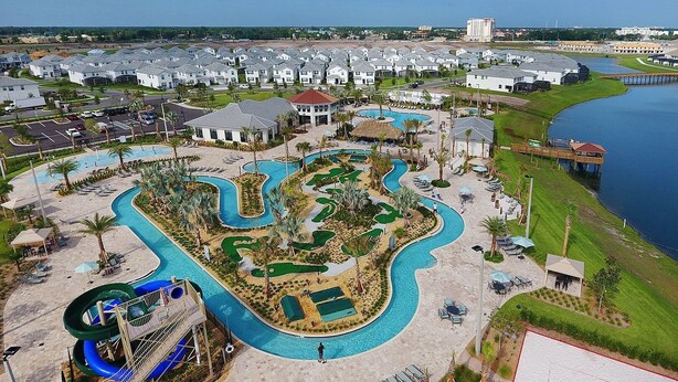 Vista aérea de un resort con una amplia zona de piscina, un tobogán de agua y un puerto deportivo.