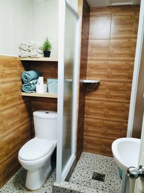 A compact bathroom with a toilet, a sink, and a shower area.