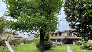 Il s’agit d’une propriété résidentielle dotée d’une pelouse bien entretenue, d’un ensemble de jeux en bois et d’un chemin de pierre menant à une maison dont le toit est recouvert de tuiles.