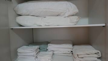 Un'area di stoccaggio con asciugamani bianchi ordinatamente impilati e coperte piegate sugli scaffali.