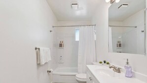 A bathroom with a shower, toilet, and sink, with a mirror above the sink. - Cozy Salt Lake Getaway - Desk w/ Monitor ! (Salt Lake City)