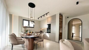 A modern kitchen with a central island, pendant lighting, and a view into the dining area.