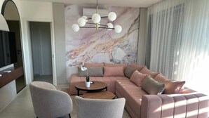 A modern living room with a sectional sofa, two armchairs, a coffee table, and a marble wall.