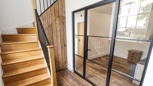 Un escalier en bois mène à une pièce dotée d’une grande porte-fenêtre coulissante.
