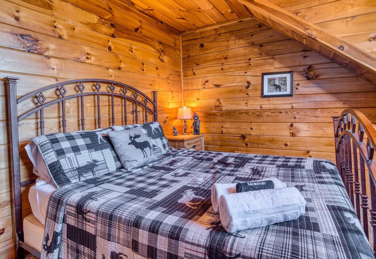 A wooden cabin room with a bed, a nightstand, and a lamp.
