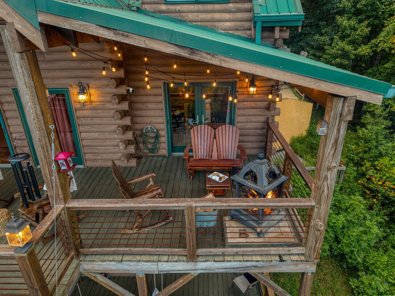 Una cabaña de troncos con terraza, asientos exteriores y chimenea.