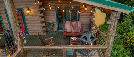 Una cabaña de troncos con terraza, asientos exteriores y chimenea.