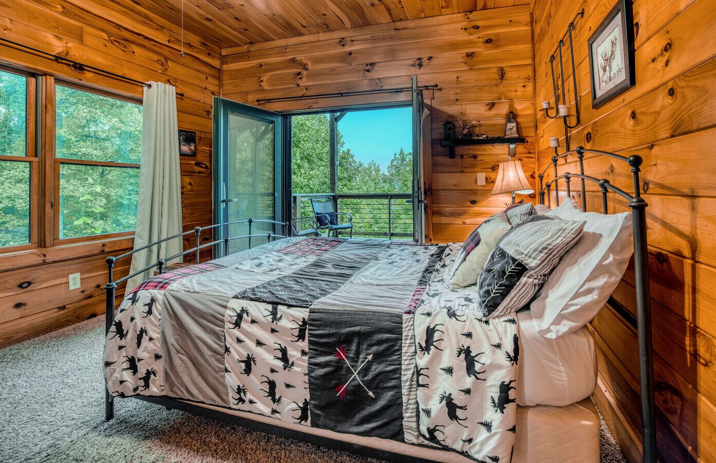 Un dormitorio de cabaña de madera con una cama, una ventana y una silla junto a la ventana.