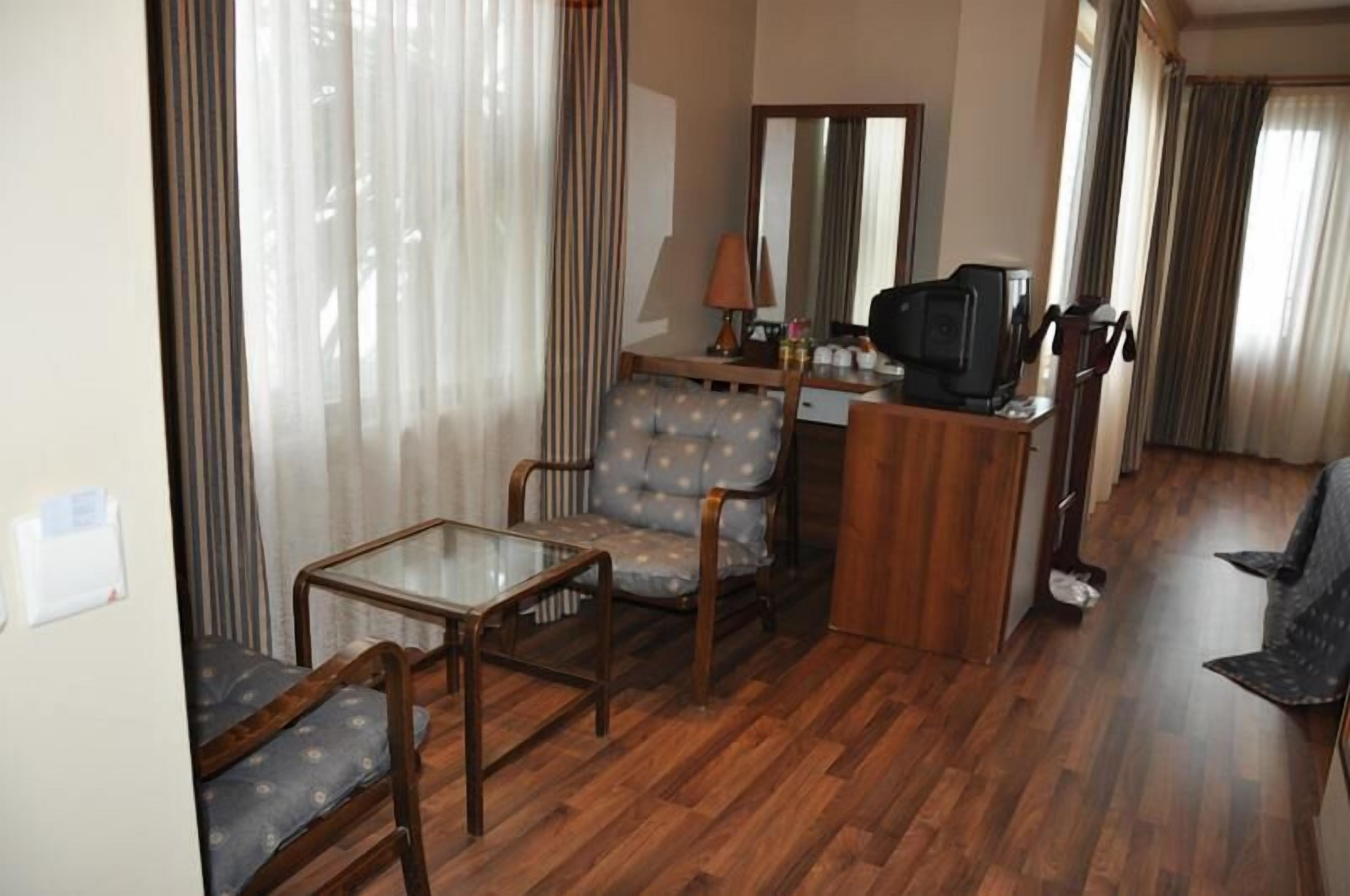 A compact living room with a sofa, a small table, a television, and a mirror.