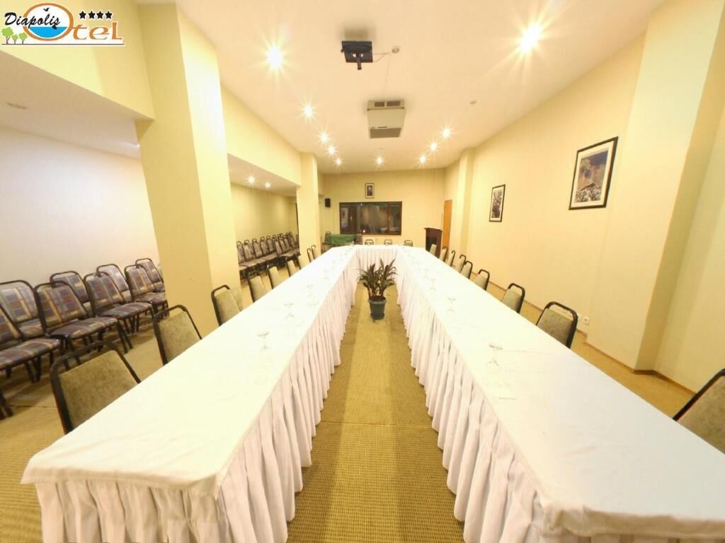 Un salón de conferencias con una larga mesa, sillas y una pantalla de proyector.