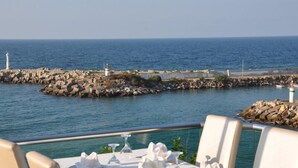 Une table dressée pour le dîner, avec vue sur la mer et un brise-lames rocheux.