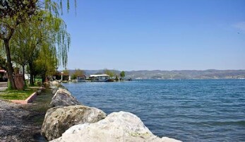 Vista de un lago con un muelle, agua tranquila y una orilla distante.