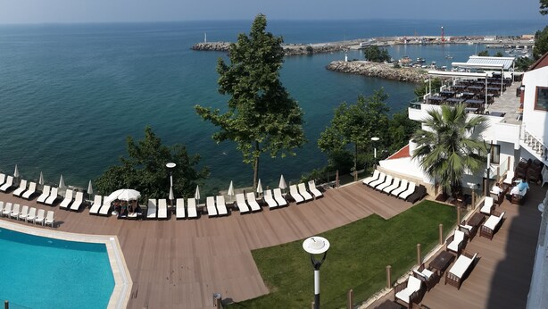 Un espace piscine aménagé sur le toit, avec des chaises longues et une vue sur la mer.