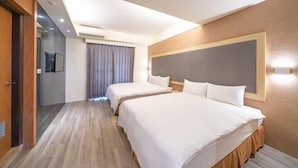 Ett hotellrum med två sängar, en stor spegel, en platt-TV och en modern takdesign.