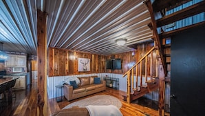 Ein Holzinnenraum mit einer Couch, einem Essbereich und einer Treppe.