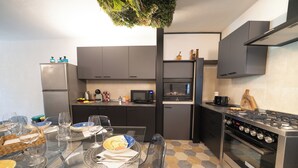 A modern kitchen with a dining area, equipped with stainless steel appliances, a microwave, and a stove.