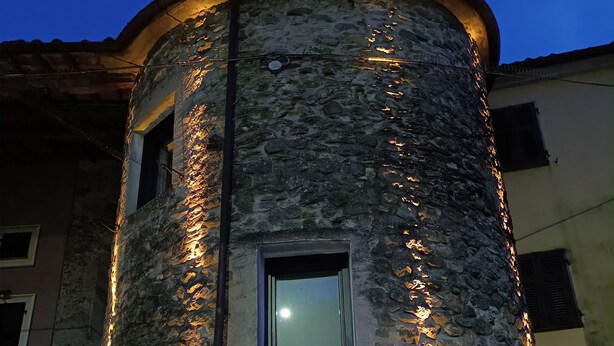 A stone tower with a window and a door, illuminated by warm lights.