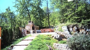 A rustic outdoor setting with a brick structure, possibly a fireplace, surrounded by greenery and a wooden bench. - Beautiful Luxury Apartment in Villa Emily With Amazing Sea View (Opatija)