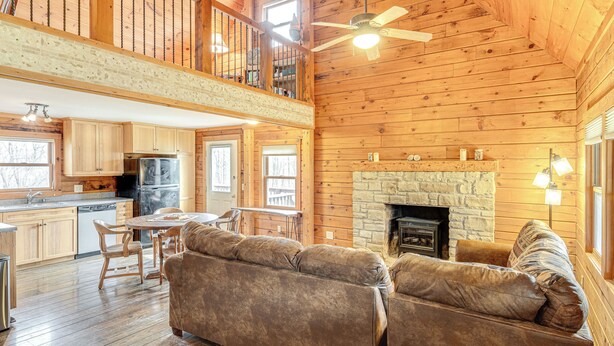 A log cabin interior with a dining area, sofa, fireplace, and kitchen. - 8 Mi to IU: Cabin w/ Reading Nook, Fire Pit & Yard (Unionville)