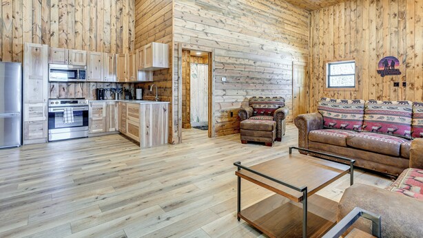A wooden interior with a kitchen, a sofa, and a coffee table. - Hunt, Fish & Boat: Northwoods Hideaway (Tomahawk)