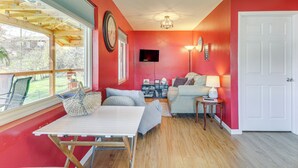Una habitación con una mesa de madera, un sofá, un televisor y una puerta.
