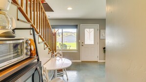 Una cocina con una escalera de madera, una puerta blanca y vistas al exterior.