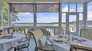 A covered outdoor dining area with tables set for two, overlooking a body of water. - Lakefront Getaway with Dock, Pool, Sunset Games (Greenwood)