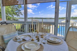 A table set for four with candles, glasses, and plates, overlooking a lake and pool. - Lakefront Getaway with Dock, Pool, Sunset Games (Greenwood)