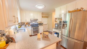 A modern kitchen with white cabinets, stainless steel appliances, and a granite countertop.