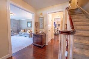 A spacious living room with a wooden staircase and a cozy seating area.