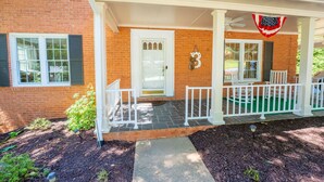 A two-story brick house with a covered porch, a front door, and a mailbox.