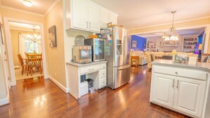 A spacious kitchen with white cabinetry, a stainless steel refrigerator, and a dining area with wooden chairs.