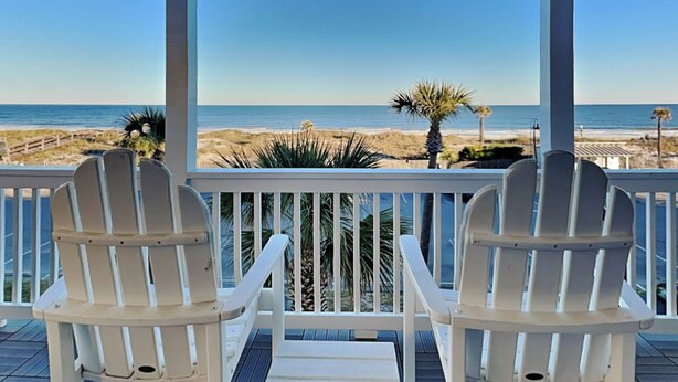 A covered deck with two white Adirondack chairs facing a beach view. - Dolphin Watch 7 Tybee Vacation Rentals (Tybee Island)