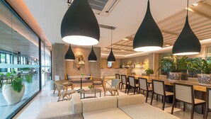 A modern hotel lobby with a seating area, a bar, and pendant lighting.