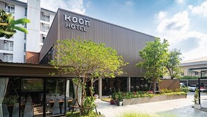 A modern hotel with a prominent sign, outdoor seating, and a landscaped courtyard.