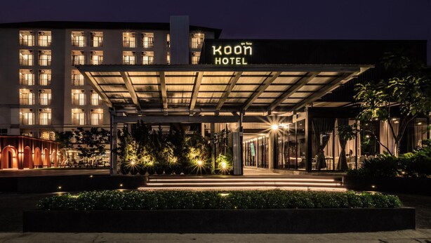 A hotel entrance with a covered walkway, illuminated windows, and a sign reading 'Koon Hotel'.