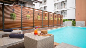 A poolside area with lounge chairs, a drink, and a hat on a table.