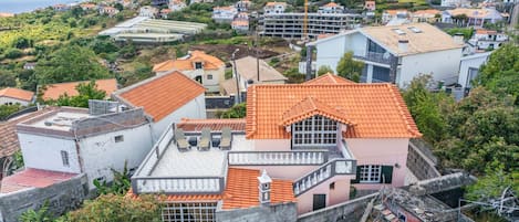 A residential area with houses, some with red-tiled roofs, and a hillside in the background.
